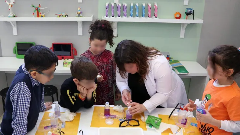 Eğitmenle birlikte deney yapan çocuklar